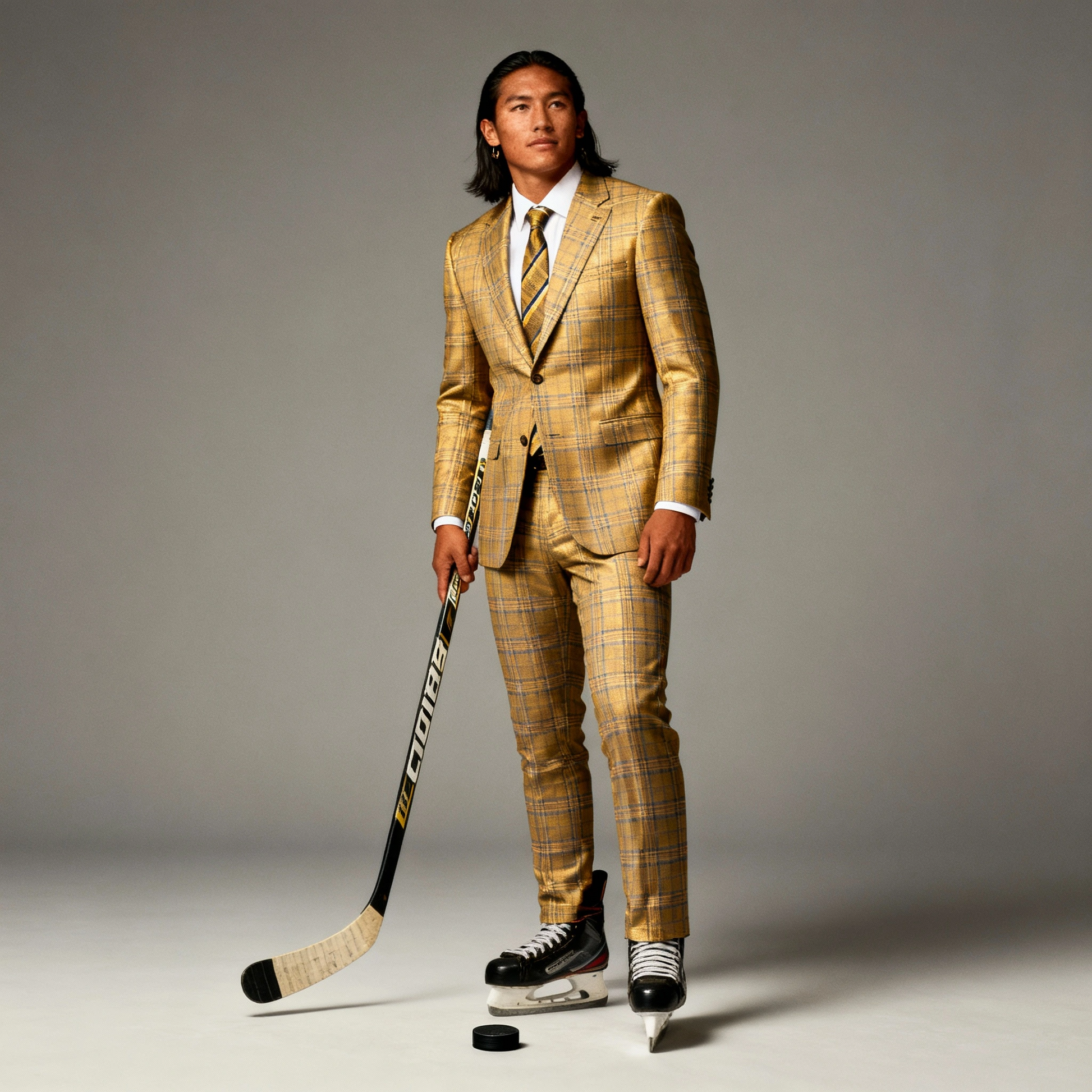 Man in a yellow plaid suit holding a hockey stick on a gray background