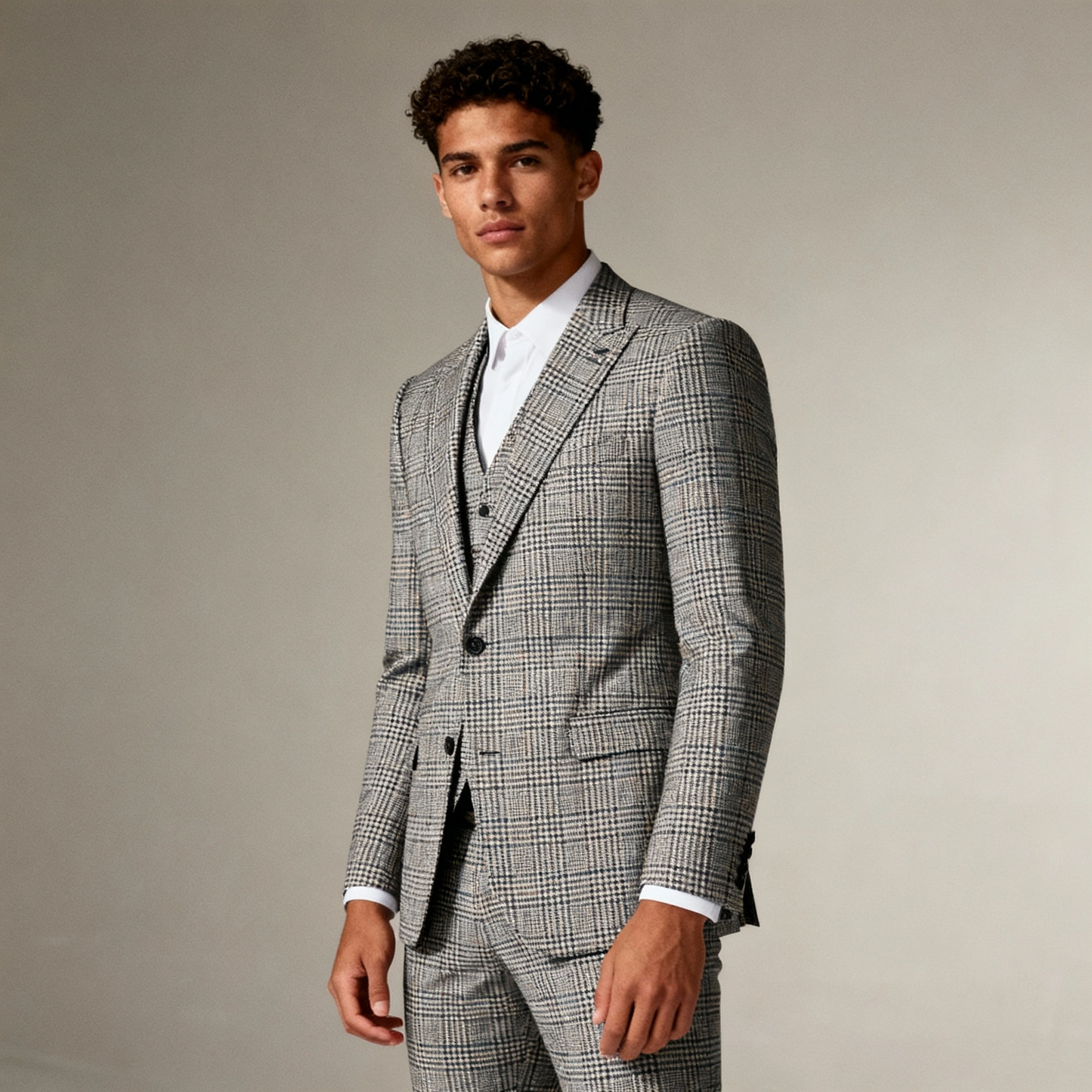 Man wearing a gray checkered suit against a plain background