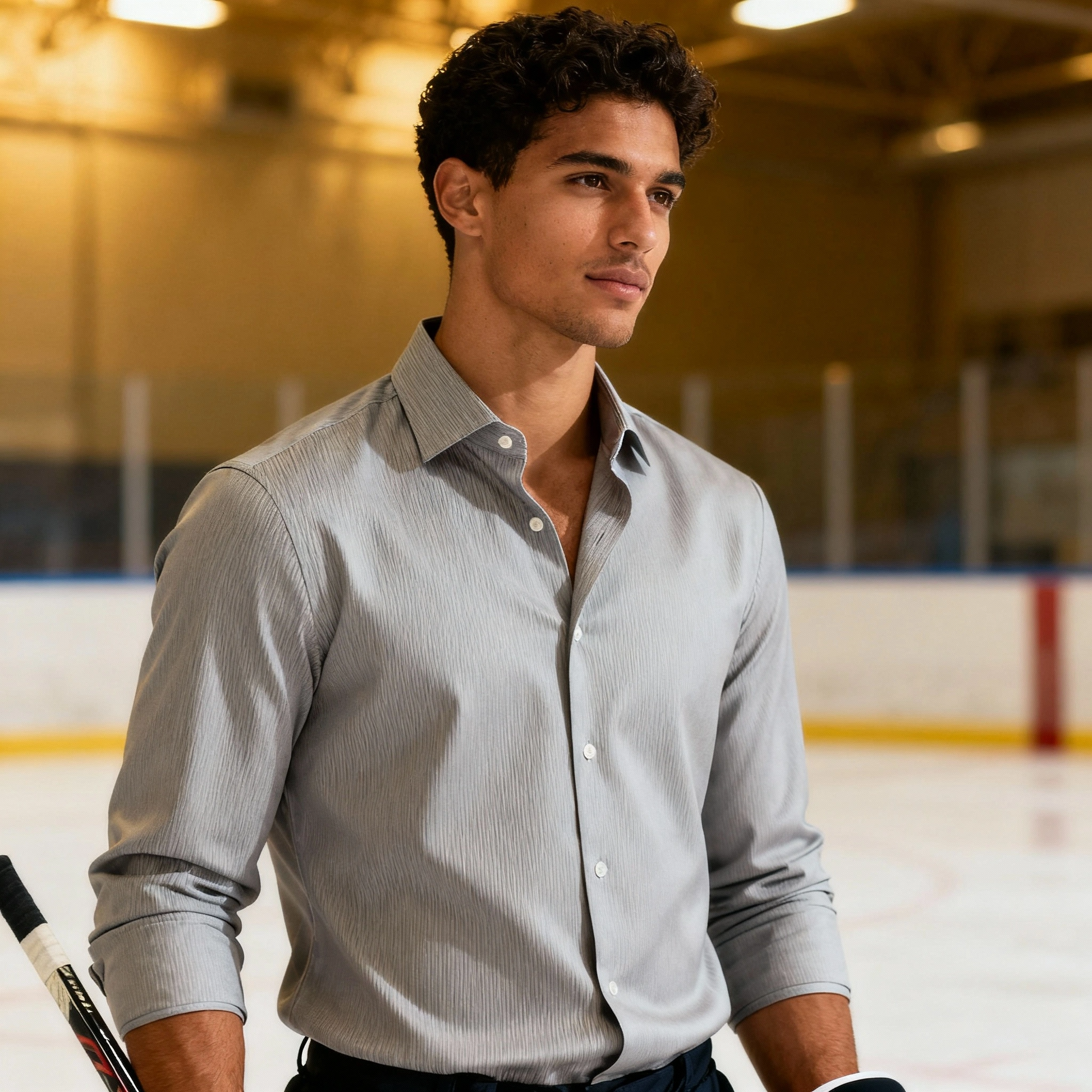 Man in a light gray shirt standing on an ice rink